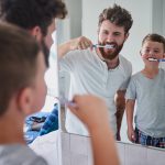Dad brushes his teeth with his son, making oral hygiene fun for his kids