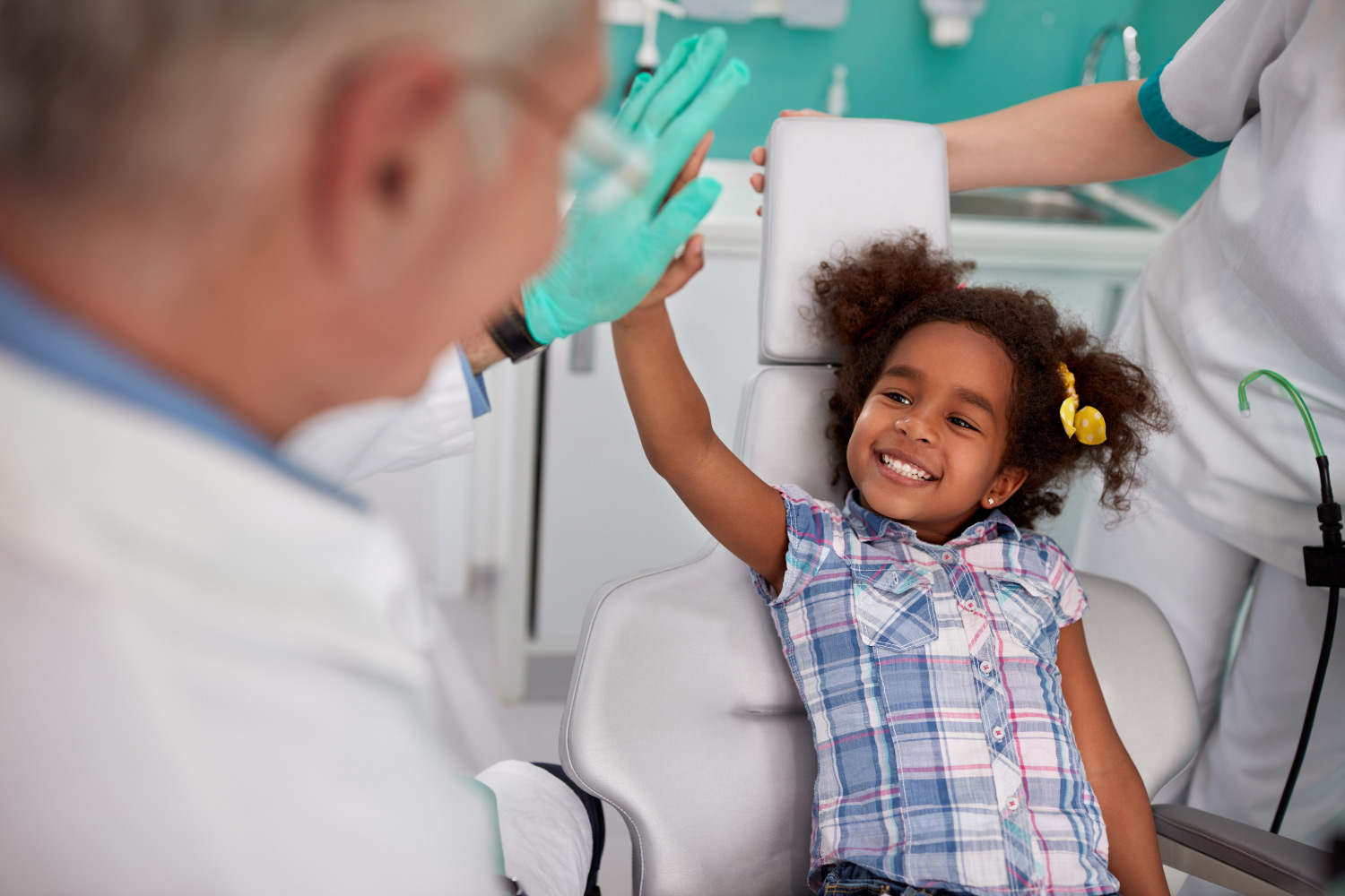 Little girl smiles and high-fives her dentist after using safe dental sedation in Denver, CO