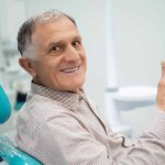 Mature man giving the thumbs up sign from the dental chair.
