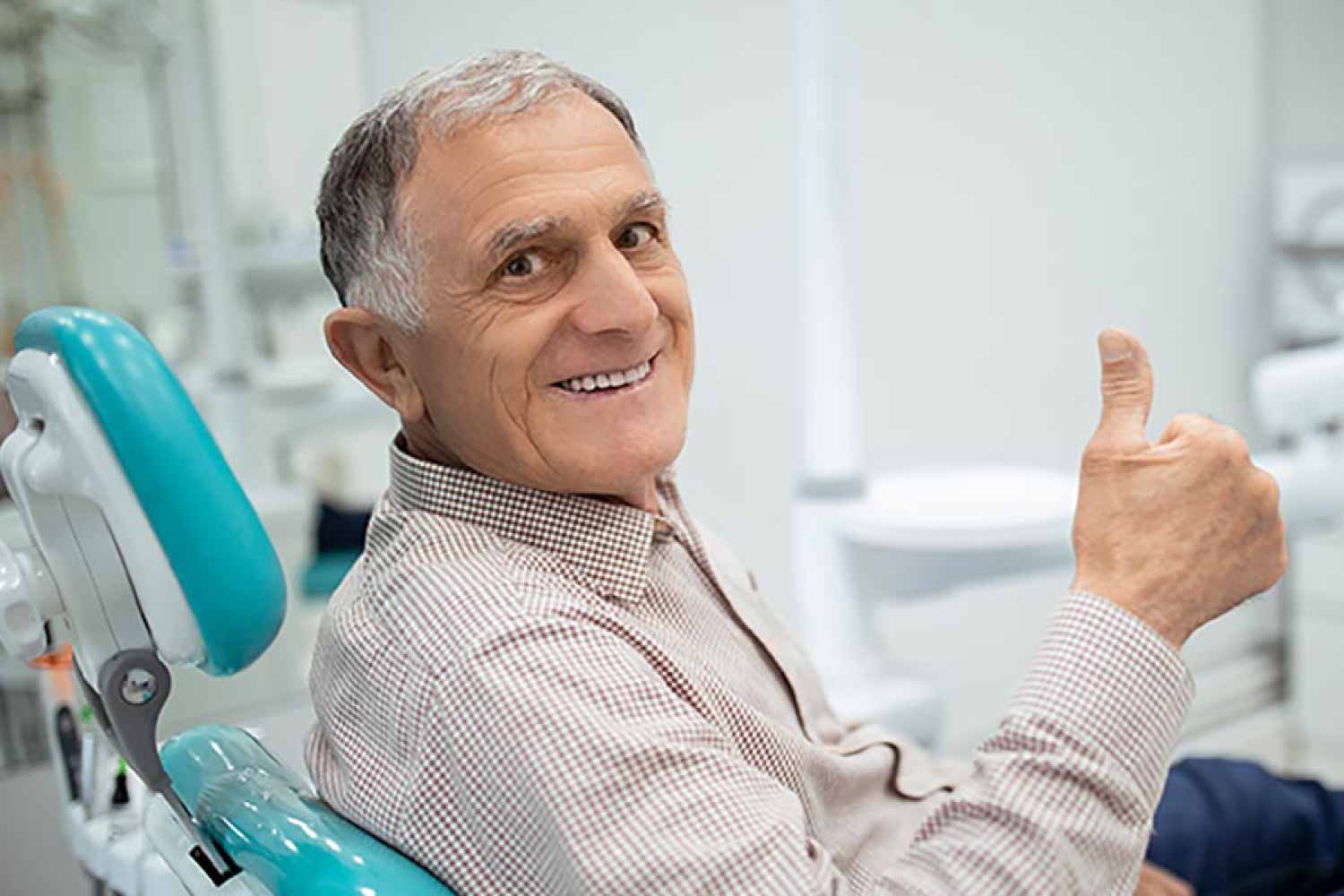 Mature man giving the thumbs up sign from the dental chair.