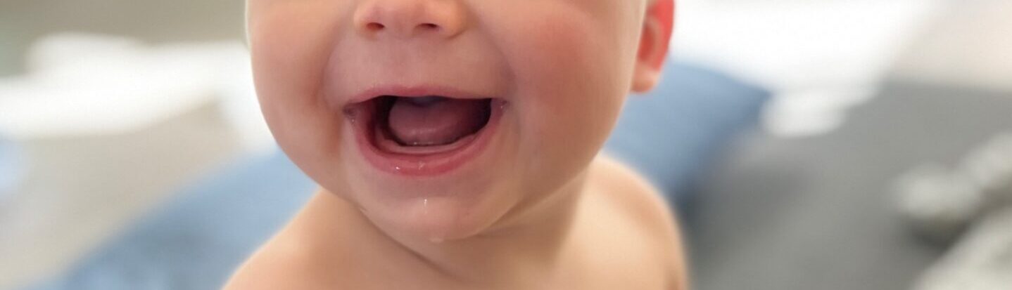 Closeup of a white baby's pink mouth with saliva dripping down his chin