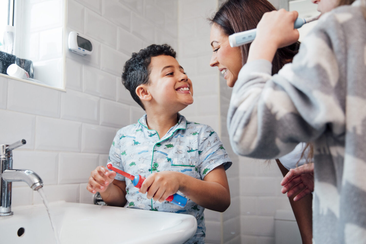 Young boy smiles at his mom after brushing his teeth at the bathroom sink