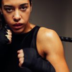 Woman martial artist in a black tanktop wears a custom mouthguard as she poses ready to box