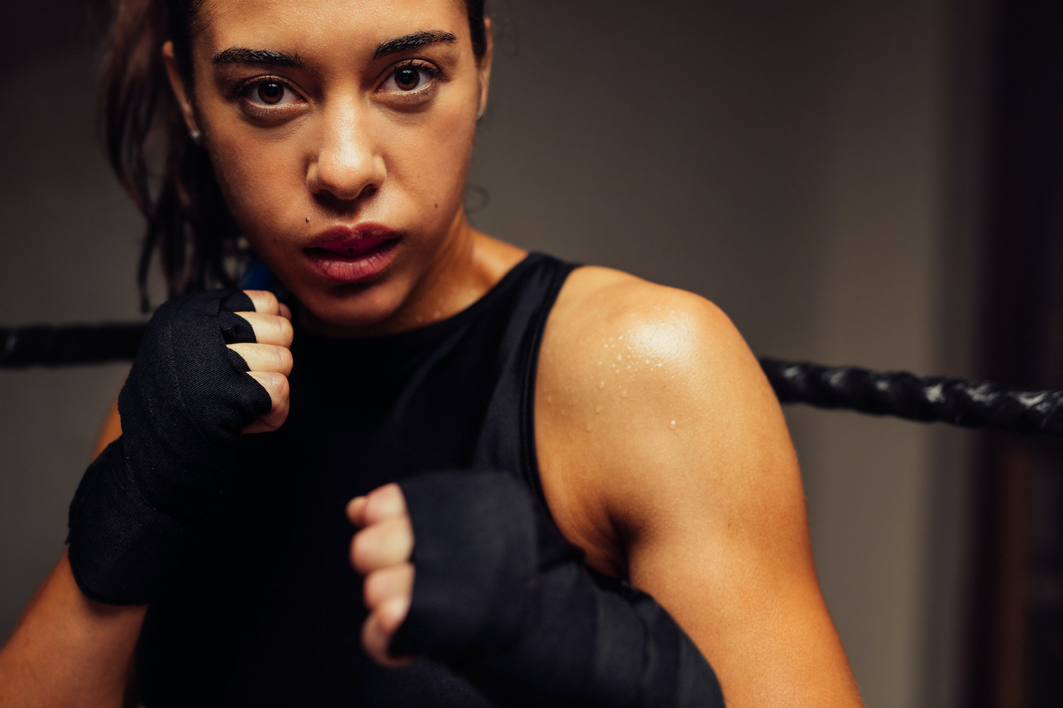 Woman martial artist in a black tanktop wears a custom mouthguard as she poses ready to box